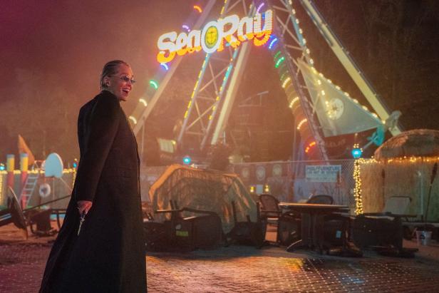 Sharon Stone is in "Nobody 2" nasty laughing with a gun in hand in front of an amusement park