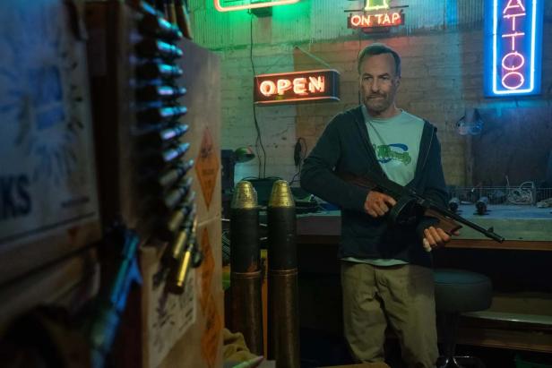 Bob Odenkirk is standing in "Nobody 2" in a back room with a fire weapon in "Nobody 2"