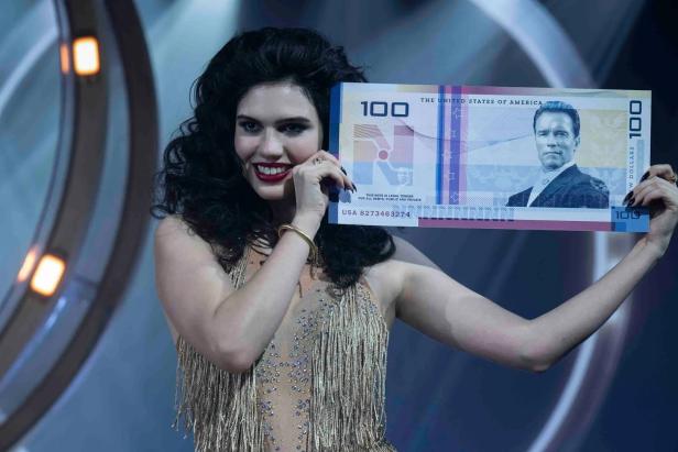 Woman holds up large banknote with Arnold Schwarzenegger motif