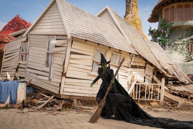 Cynthia Erivo in front of a half-collapsed wooden house