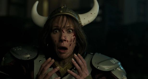 Woman wearing Viking helmet has blood spattered on her face and looks scared