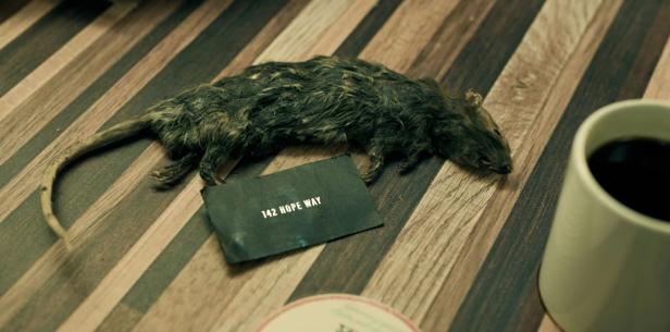 Dead mouse lies on a table next to a coffee cup