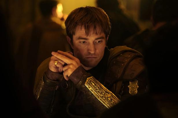 Man in antique robe with golden bracers looks thoughtfully ahead