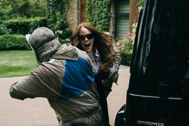 Woman is attacked by man in protective suit in front of car in driveway