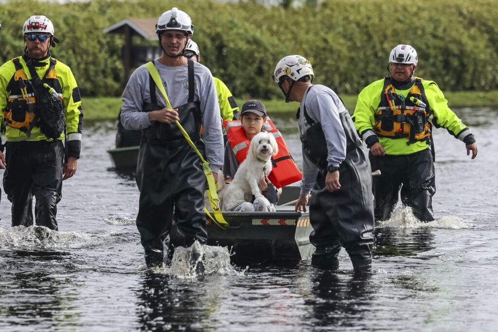 Florida residents make their way through flooded streets and collect debris after Milton