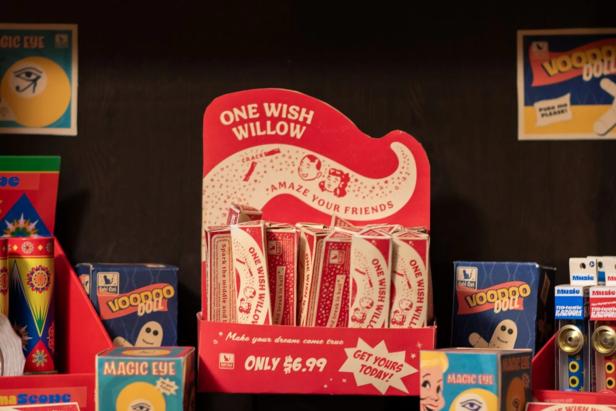 A display for One Wish Willow wishbones sits on a shelf surrounded by voodoo dolls and Magic Eye boxes.